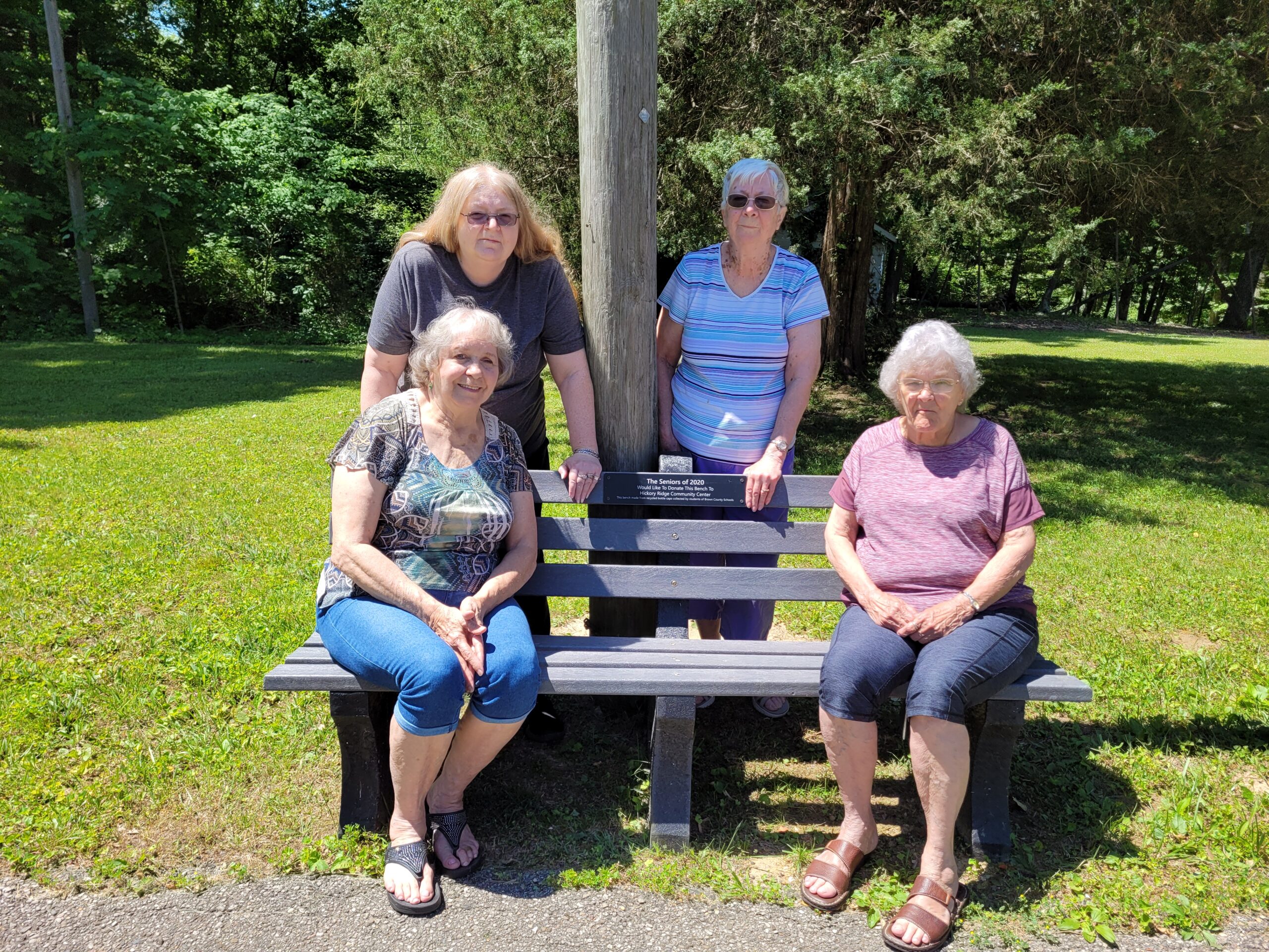 Group of senior citizens sitting on a bench by the paved walking track